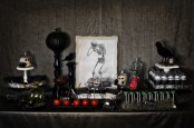 a vintage Halloween dessert table with candied apples, various desserts, a black pumpkin on a stand and a crow is chic and stylish