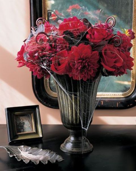 an easy Halloween arrangement of red roses and lotus swirls plus spiderwebs can become a centerpiece, too