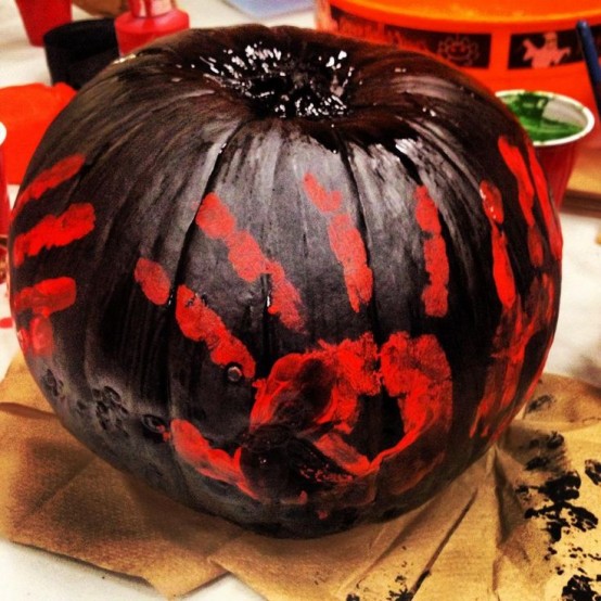a scary black Halloween pumpkin with red palm prints is a stylish decoration you may rock