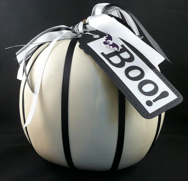 a white pumpkin with black and white ribbons and a black and white tag is a cool minimalist Halloween decoration to rock