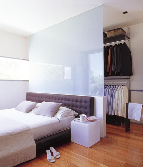 a walk-in closet divided from the bedroom with a frosted glass half wall is a cool and smart solution thatgivesenough light to the closet, too