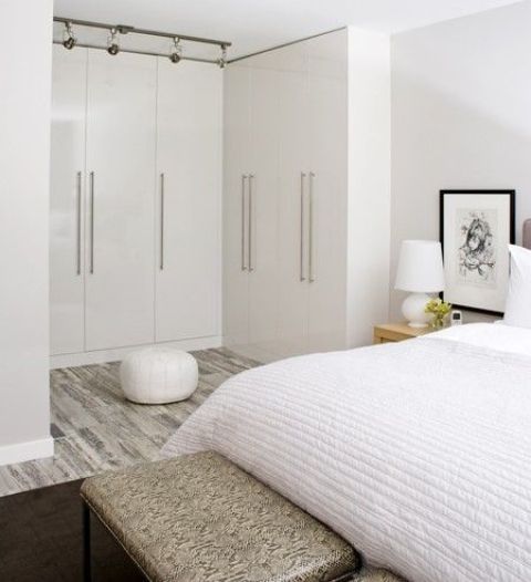 a neutral and stylish bedroom with a whole arrangements of wardrobes forming a personal walk-in closet - that's a very smart and cool idea