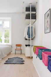a stylish makeshift closet with open shelves and dressers, with boxes and additional colorful baskets for storage is all cool