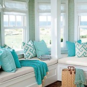 a beach sunroom with built-in benches, tiffany blue and printed pillows plus a cool coastal view