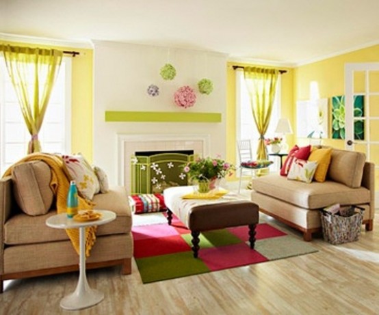 a bright and colorful spring living room with yellow accent walls and curtains, with a colorful square rug, bright pillows and blankets and a green fireplace screen