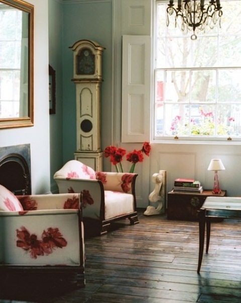 a refined spring living room with vintage touches, with floral chairs, a vintage crystal chandelier, refined decor and clocks