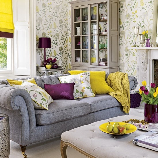 a bright spring living room with floral walls, a grey sofa, yellow and purple accessories, linens and lamps
