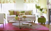 a bright and fun living room with floral and green textiles, a pink floral rug, a green ottoman and greenery and blooms
