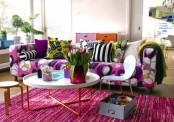 a bright spring living room with a floral print sofa, printed pillows, a pink rug and bold blooms and greenery