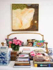 a bright and fun living room with a statement artwork, a refined sofa with colorful pillows, blooms and books is whimsical