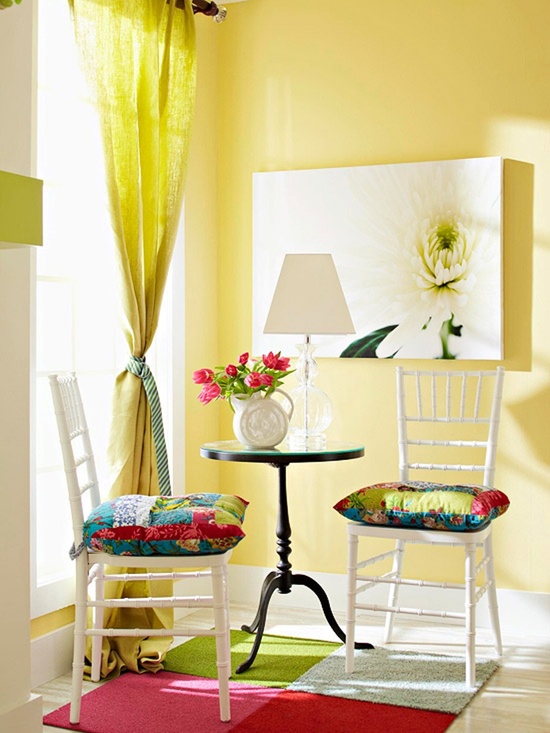 a bold living room with yellow walls, a yellow curtain, colorful pillows and artworks and a bright rug