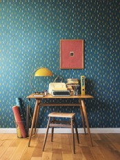 an elegant home office with plenty of color – dark green printed wallpaper, mid-century modern furniture, a yellow table lamp and a bold artwork is a lovely space to be in
