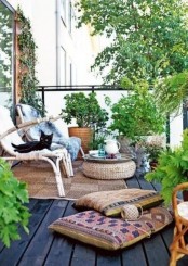 a lovely boho balcony with potted greenery, a jute rug and a pouf, rattan chairs and bright boho pillows is a very stylish and welcoming space