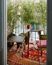 a bright boho balcony with colorful boho rugs, wood, cane and rattan furniture, potted greenery used for privacy and decor