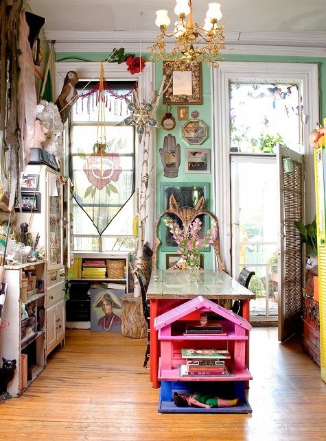 green walls and pink and red furniture with eclectic artworks and textiles