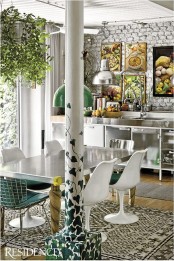 colorful artworks, a unique pillar, dark green chairs and printed rugs for a catchy look