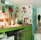 a colorful home office or crafting space with mint blue walls, a turquoise accent wall, a green vintage desk and a colorful gallery wall over the desk