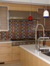 a light-stained kitchen with taupe upper cabinets, a colorful mosaic tile backsplash and colorful pendant lamps that echo with it