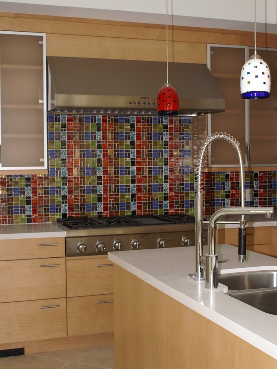 a light stained kitchen with taupe upper cabinets, a colorful mosaic tile backsplash and colorful pendant lamps that echo with it