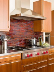 a light-stained kitchen with a bold rust, burgundy and deep red mosaic tile backsplash looks very retro-like and very bold