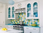 a white kitchen with shaker cabinets, with glazed cabinets, blue countertops and a green and blue geometric tile backsplash is a fun and bold idea