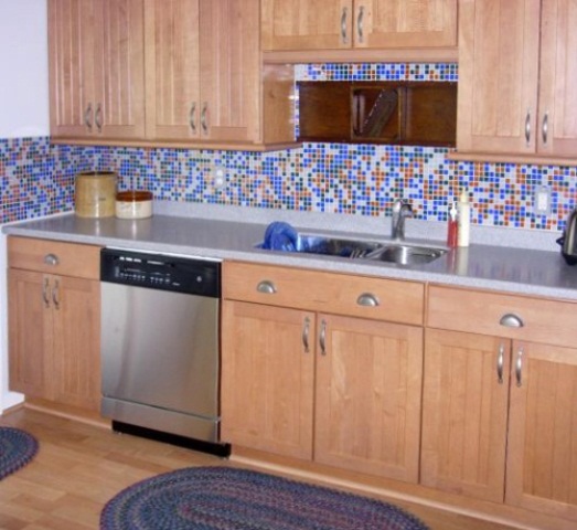 a light stained kitchen with shaker cabinets, grey countertops and a super colorful mosaic tile backsplash is a fun idea
