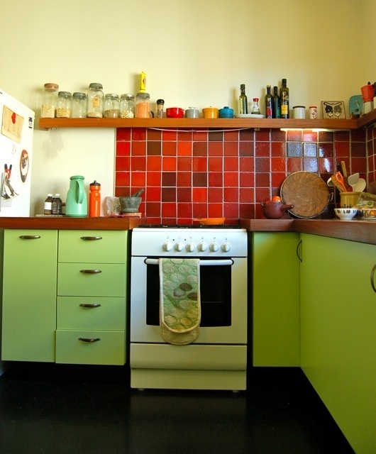 a neon green kitchen with rich-stained countertops, red, brown and rust mosaic tiles that are used to contrast the kitchen color