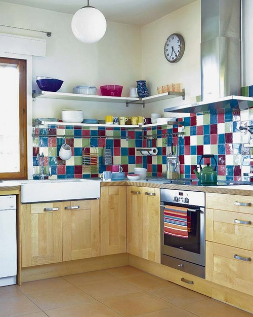 a light-stained kitchen with shaker cabients, butcherblock countertops and a super colorful burgundy, pink, blue and white tiles that creates a mood in this space