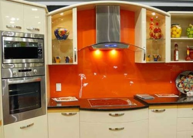 a neutral kitchen with an orange glass backsplash and built in appliances is a lovely idea of a cheerful space