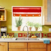 a colorful kitchen with mustard walls, sleek stained cabinets, a stone countertop and a bright mosaic tile backsplash plus a bright curtain is fun and cheerful