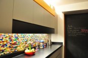a sleek grey and black minimalist kitchen with a black countertop and a super colorful backsplash and built-in lights is amazing