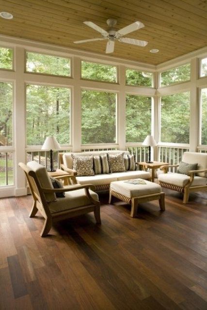 a serene and airy screened patio with neutral seating furniture with neutral upholstery, table lamps and greenery around is wow