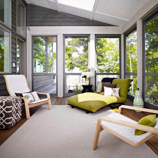 a screened patio with neutral loungers, a green daybed, some pilllows, greenery and blooms is amazing