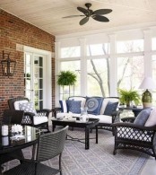 a mid-century modern porch with black wicker furniture with white and blue upholstery, potted greenery and table lamps and a cool view