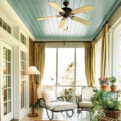 a mid-century modern screened porch with cool indoor furniture, chairs and loungers, potted greenery and blooms and some lamps