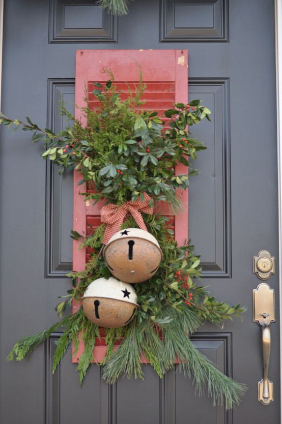 lovely and chic rustic front door decor with greenery and fir branches, berries, a plaid bow and oversized bells with stars