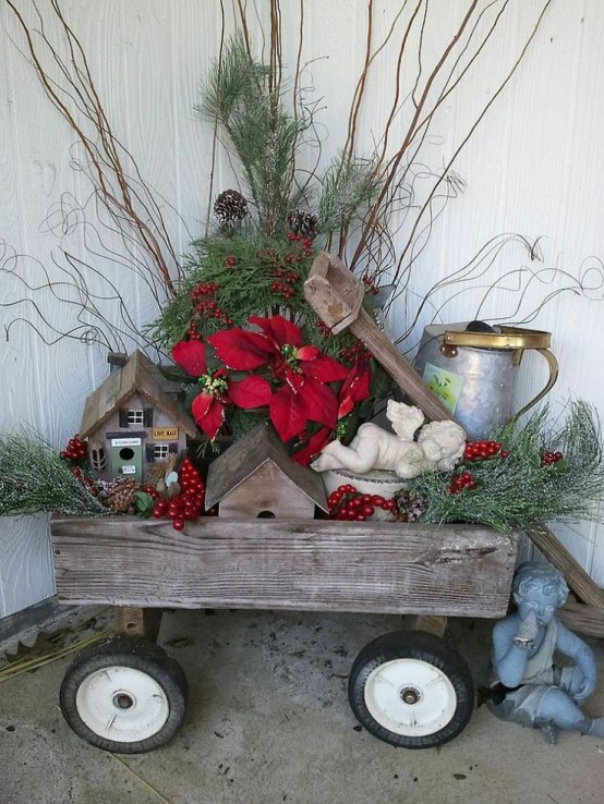 a wooden cart with berries, greenery, red blooms, branches, mini houses and a bucket will make your front porch rustic and cozy