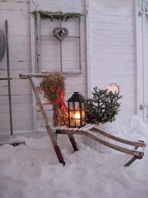 a rustic decoration - a lounger with dried herbs, a lantern, fir branches in a pot and a window frame with a vine heart for your backyard or front one