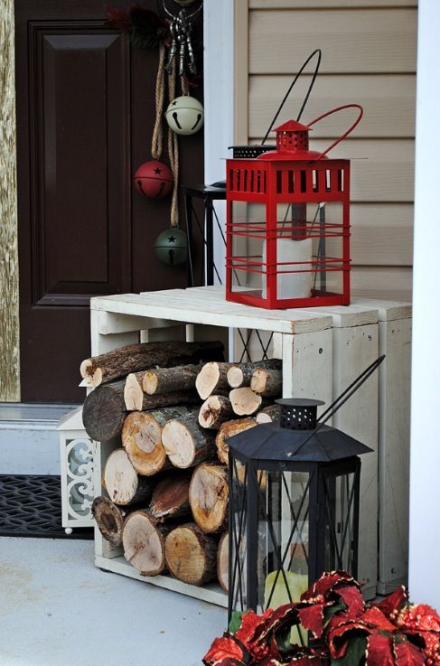 a crate with firewood, oversized candle lanterns and bright bells hanging on the door for a festive and rustic feel
