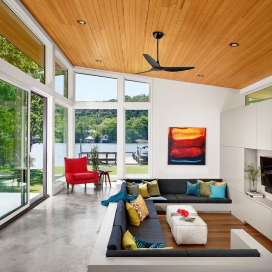 a modern living room with a conversation pit, a large white storage unit, a grey sofa with lots of pillows and a coffee table