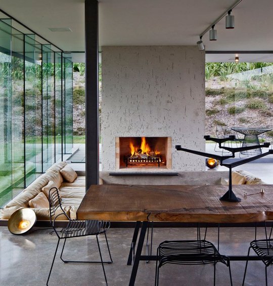 a glazed living room with a fireplace, a conversation pit and neutral sofas in it, a great space to relax and have a talk