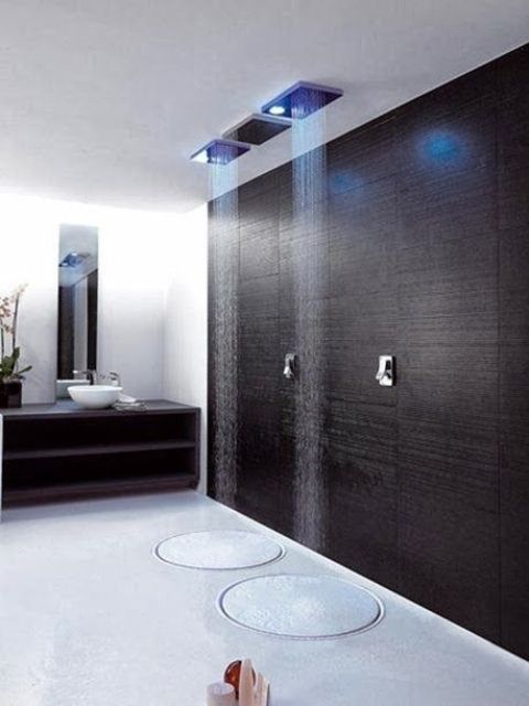 a minimalist shower with a dakr accent wall, just two rounds on the floor and colored lights plus two rain showers for a minimalist bathroom