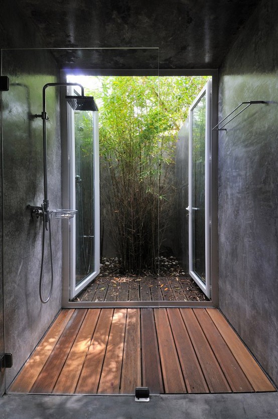 a contemporary outdoor-indoor shower with a wooden floor, stone walls and an exit to the private backyard