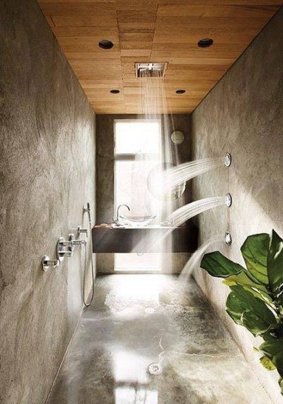 a modern tropical bathroom with a built-in vanity and sink, concrete walls and a floor, a rain shower and shower integrated into the walls