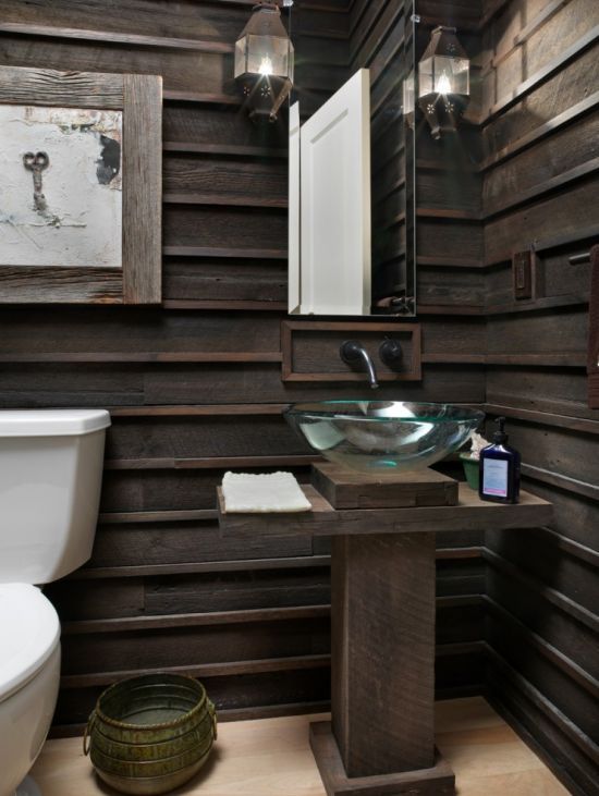 a dark-stained sculptural wooden vanity matches the wood paneling on the walls and continues with the rustic style of the space