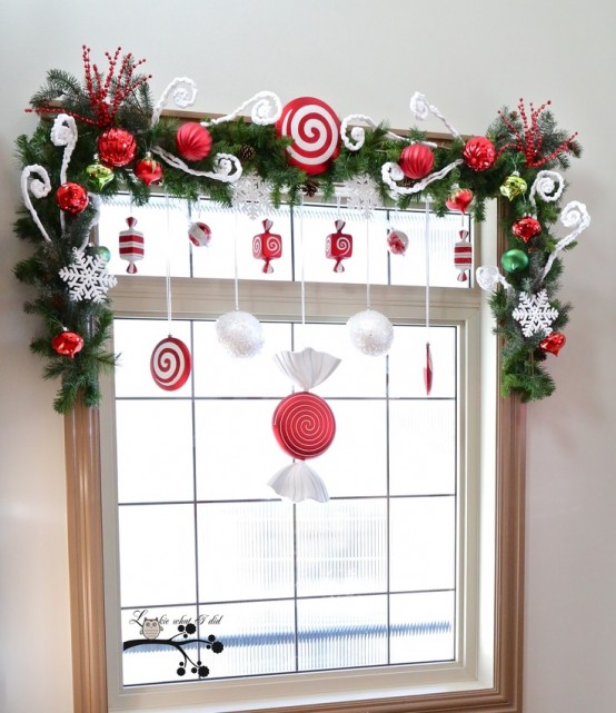 pretty and cute Christmas window decor with fir garlands, red and white ornaments, snowflakes and candies is a very cool idea for a kids' room
