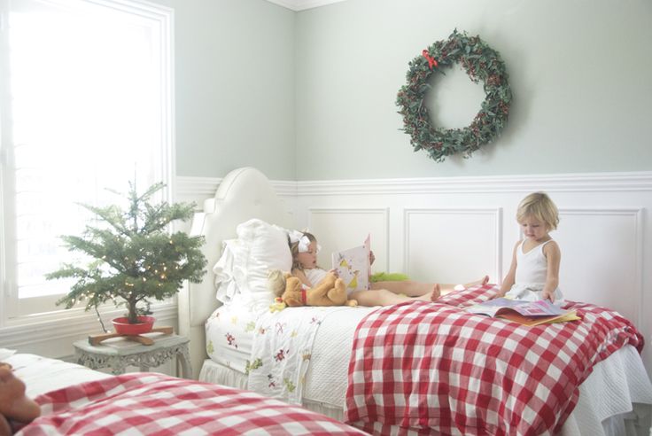 a wreath, a potted Christmas tree with lights and red plain bedding bring a holiday feel to this shared kids' room