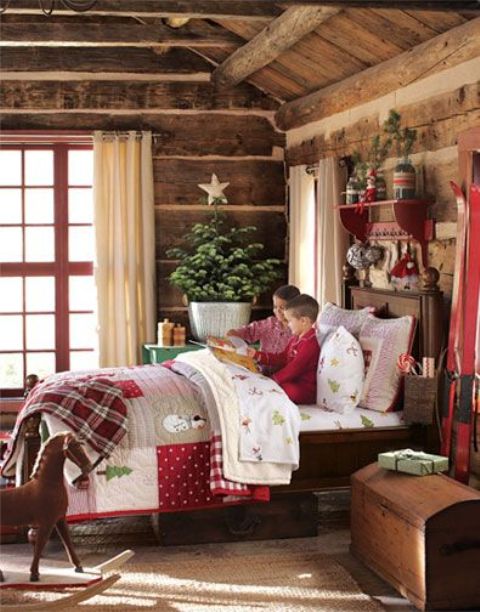 a rustic kids' room decorated for Christmas with bright bedding and blankets, a Christmas tree with a star topper and some branches over the bed