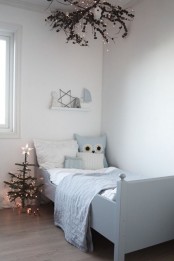 a simply decorated Christmas tree and some branches with pinecones and lights over the bed for a cozy holiday ambience in the room