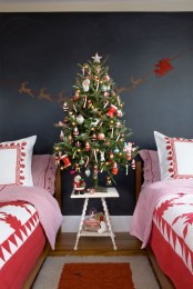 a Christmas tree decorated with bright ornaments and star banners and garlands is a lovely idea to rock in your kids’ room, add holiday printed bedding